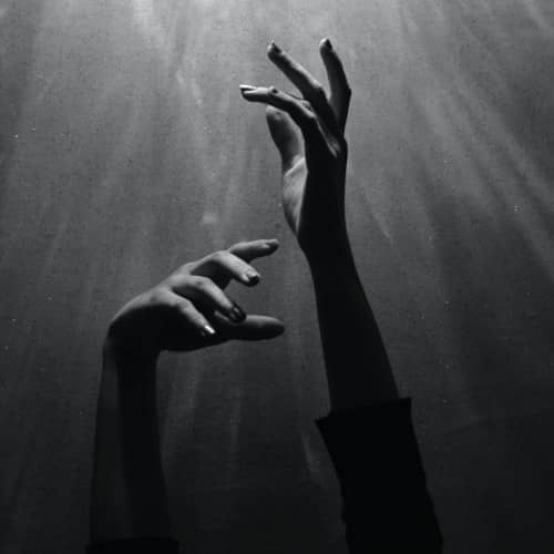 Photo noir et blanc de deux mains tendues vers le haut