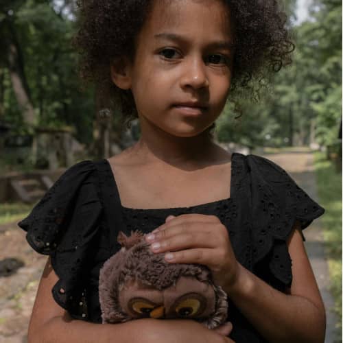 Photo d'une petite fille noire avec une peluche dans ses mains