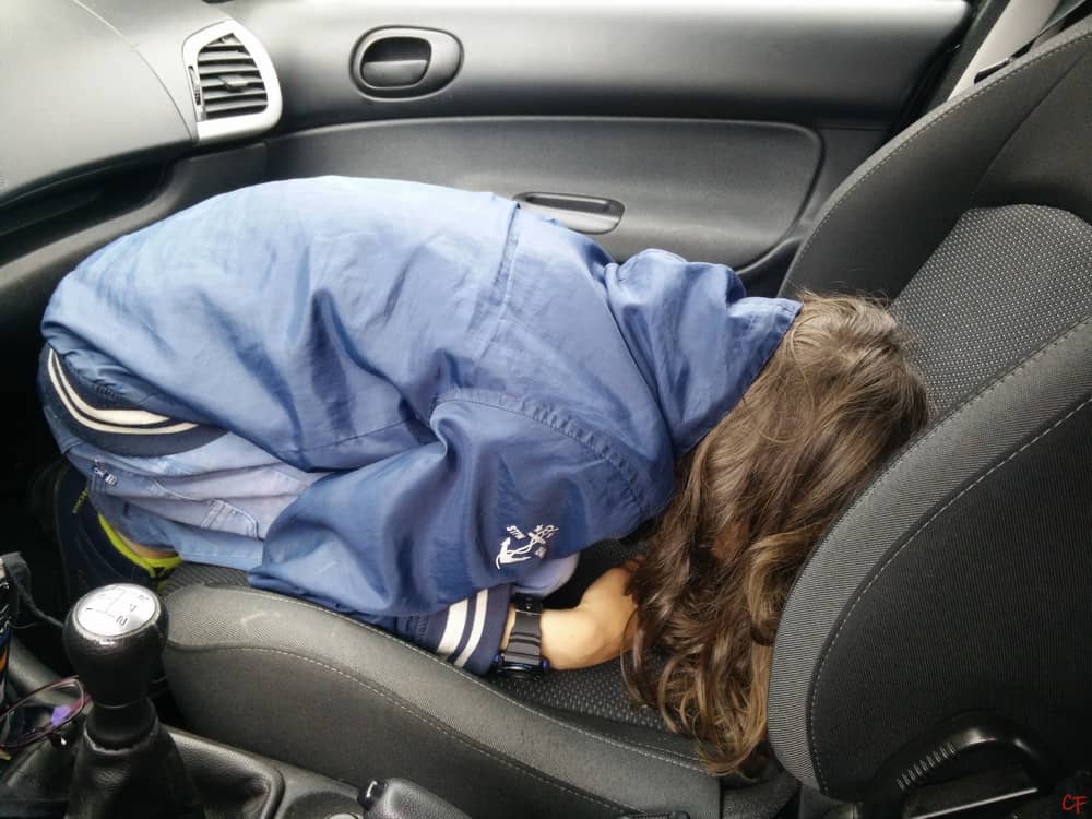 Photo d'un adolescent recroquevillé sur lui-même sur la place passager avant de la voiture