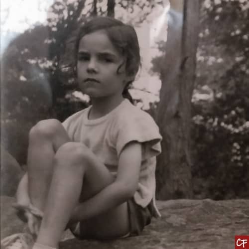 Photo noir et blanc de Chris Falcoz enfant, une petite fille qui ne sourit pas assise sur un rocher